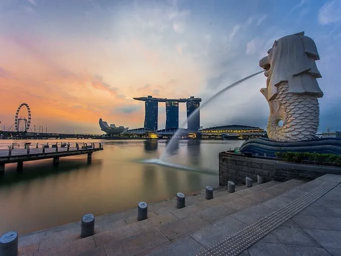 Sunrise view of the Merlion statue spouting water with Marina Bay Sands and the Singapore Flyer in the background